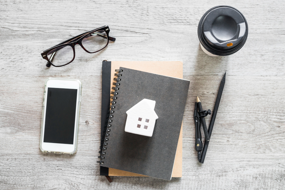 A wooden table displays a notebook, glasses, a phone, and a coffee cup, suggesting a productive work environment